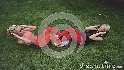 Deux blondes, deux soeurs jumelles, font des exercices sportifs sur l'herbe verte, été ensoleillée, vue de haut banque de vidéos Deux blondes, deux soeurs jumelles, font des exercices sportifs sur l'herbe verte, été ensoleillée, vue de haut banque de vidéos
