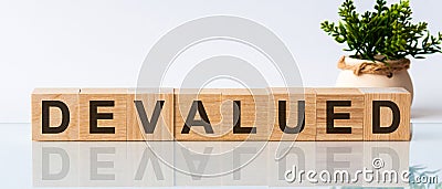 DEVALUED text on wooden blocks business concept white background. Front view concepts, flower in the background. Stock Photo