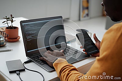 Developer connecting smartphone with laptop to work with codes Stock Photo