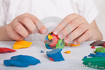 Development of small motor skills of children. A child sculpts a colorful ball of plasticine Stock Photo