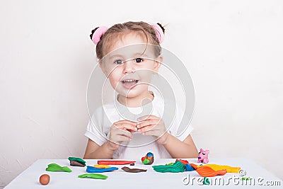 Girl sculpts from plasticine pig and bunny. Stock Photo