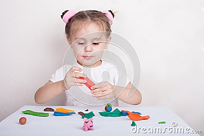 Girl sculpts from plasticine pink pig Stock Photo