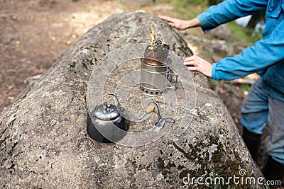 A fire in a woodchip and a kettle, flint. A man in a blue clothes on background Stock Photo