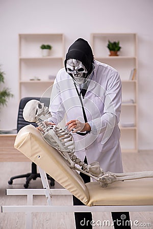 Devil doctor examining skeleton patient Stock Photo