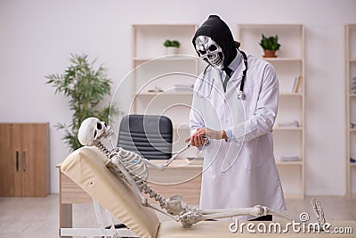 Devil doctor examining skeleton patient Stock Photo