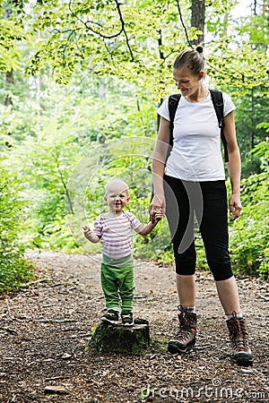 Devoted mother holding hands with her son, walking in the woods Stock Photo