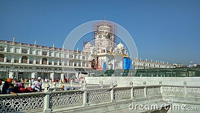 Devotees walking around the white clock tower building Editorial Stock Photo