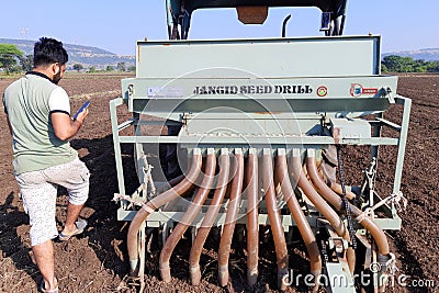 24-08-2021 Dewas, Madhya Pradesh, India, Garlic sowing by tractor, the process of planting garlic cloves in the field. The concept Editorial Stock Photo