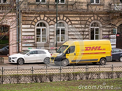 DHL package delivery service truck, van, vehicle parked on the street near a building, DHL German logistics courier company, urban Editorial Stock Photo