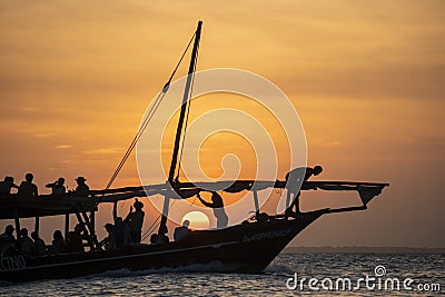 Dhow sailing during sunset in Zanzibar. Dhow is a wooden vessel with a sail, used to transport goods. Mostly used in Stock Photo