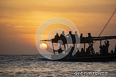 Dhow sailing during sunset in Zanzibar. Dhow is a wooden vessel with a sail, used to transport goods. Mostly used in Stock Photo