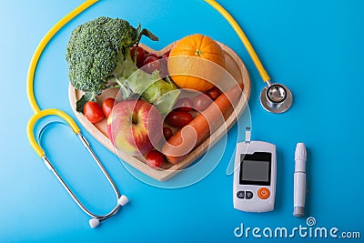 Diabetes monitor, diabetic measurement. World diabetes day concept with clean fruits in nutritionist`s heart dish..Healthy food or Stock Photo