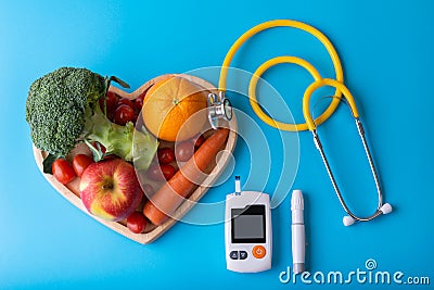 Diabetes monitor, diabetic measurement. World diabetes day concept with clean fruits in nutritionist`s heart dish.Healthy food or Stock Photo