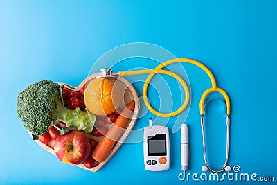Diabetes monitor, diabetic measurement. World diabetes day concept with clean fruits in nutritionist`s heart dish.Yellow stethosco Stock Photo