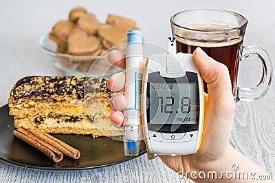 Diabetes and unhealthy eating concept. Hand holds glucometer and sweets. Stock Photo