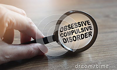 Diagnosis of Obsessive Compulsive Disorder under magnifying glass in hand. Causes, symptoms, diagnosis and treatment of this Stock Photo