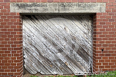 Diagonal faded wooded shipping receiving loading dock door red brick building alley Stock Photo