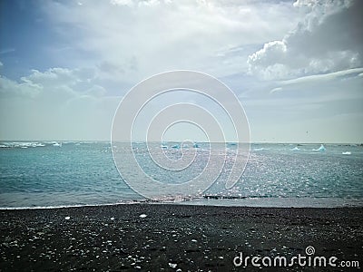 Diamond Beach in Iceland with blue icebergs melting on black sand and ice glistening with sunlight Stock Photo