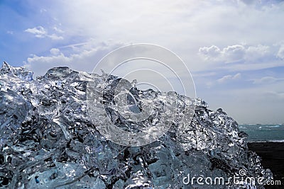 Diamond Beach in Iceland with blue icebergs melting on black sand and ice glistening with sunlight Stock Photo