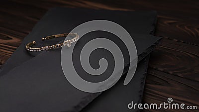 Diamond golden bracelet on rough textured stone plates on wooden table Stock Photo