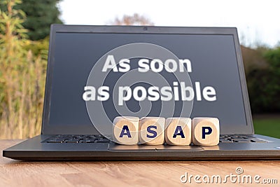 Dice form the abbreviation `ASAP`. Dice placed on a Notebook. The text `as soon as possible` is written on the display. Stock Photo
