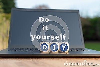 Dice form the abbreviation `DIY`. Dice placed on a Notebook. The text `Do it Yourself` is written on the display. Stock Photo