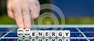 Dice form the expression 'wind energy' and 'solar energy' on top of a solar panel. Stock Photo