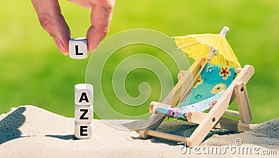 Dice placed next to a beach chair form the word `laze` Stock Photo