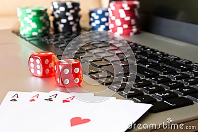 Dice, poker chips and playing cards on laptop. The concept of on Stock Photo