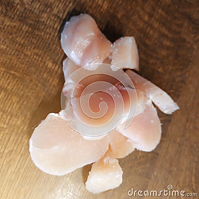 Diced chicken pieces of healthy lean white meat on a cutting board, filleted for cooking Stock Photo