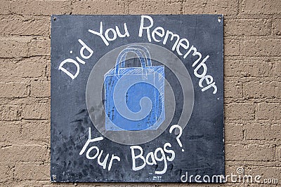 Did you Remember your bags- Sign board painted black screwed onto painted concrete block wall Stock Photo