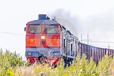 A diesel locomotive pulls a train of freight cars across the fields. Front view Editorial Stock Photo