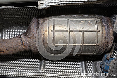 A diesel particulate filter in the exhaust system in a car on a lift in a car workshop, seen from below. Stock Photo