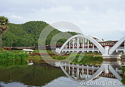 Diesel Train passing the Tha Chom Phu railway bridge or white bridge Stock Photo