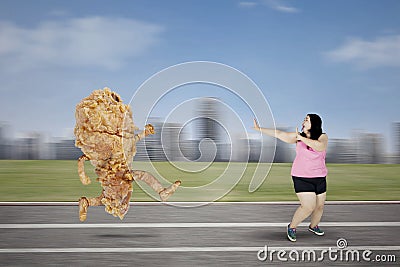 Obese woman escaping from a fried chicken Stock Photo