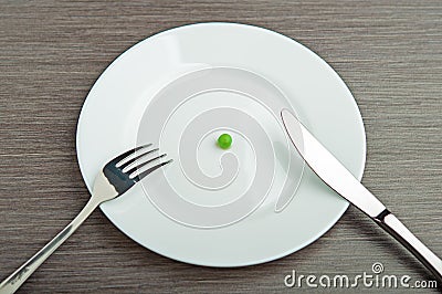 Diet concept. one pea on an empty white plate Stock Photo