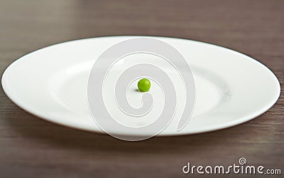 Diet concept. one pea on an empty white plate Stock Photo