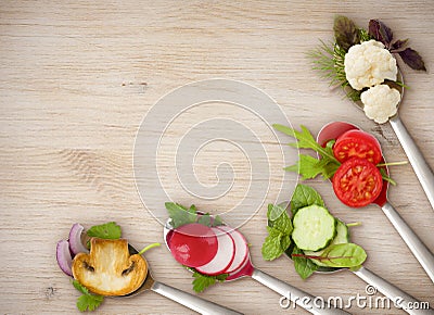 Diet concept of spoons with sliced vegetables on wooden board Stock Photo