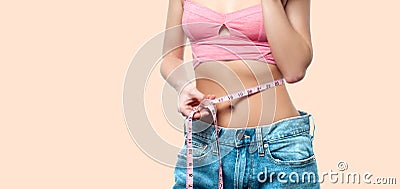 Woman is measuring waist after weight loss on faded pastel background Stock Photo