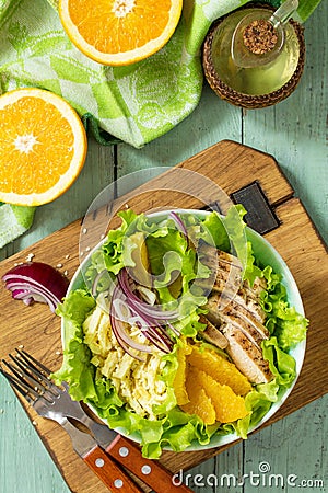 Diet menu. Healthy salad with chicken, egg pancakes, orange, green salad and dressing vinaigrette on wooden table. Stock Photo