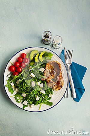 Diet menu. Healthy salad of fresh vegetables: tomatoes, avocado, arugula with cubes Goat cheese and Lamb chop in a plate. Top view Stock Photo