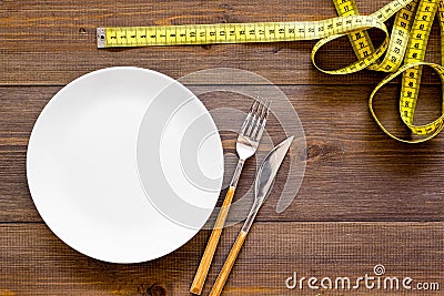 Diet for weight loss concept. Proper nutrition. Medical starvation. Empty plate with fork and knife near measuring tape Stock Photo