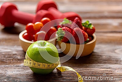 Diet and weight loss with green apple with measuring tap and fitness equipment, fresh fruits salad healthy on wooden background to Stock Photo