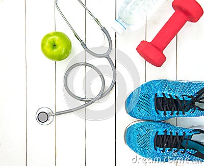 Diet and weight loss for healthy care with medical stethoscope, fitness equipment,measuring tap,fresh water and green apple on woo Stock Photo