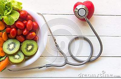 Diet and weight loss for healthy care with medical stethoscope, with red heart and fresh vegetable salad and healthy food on woode Stock Photo