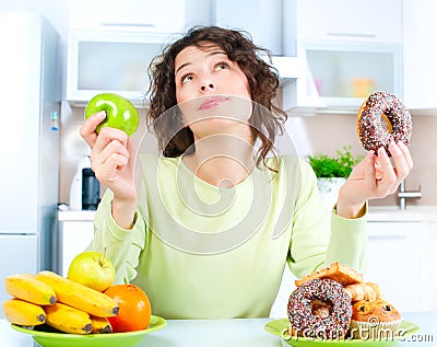 Diet. Woman choosing between Fruits and Sweets Stock Photo