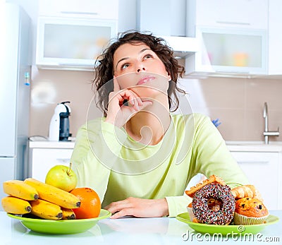 Diet. Woman choosing between Fruits and Sweets Stock Photo