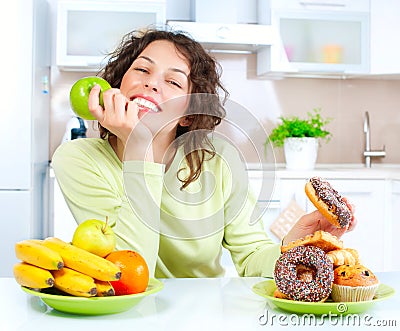 Diet. Woman choosing between Fruits and Sweets Stock Photo