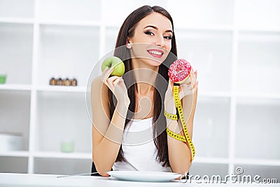 Diet. Woman Measuring Body Weight On Weighing Scale Holding Donut and apple. Sweets Are Unhealthy Junk Food. Dieting, Healthy Eat Stock Photo