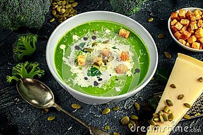 Dietary Broccoli smooth cream soup with sprinkle of sunflower seeds, parsley leaves and croutons on stone table. Stock Photo